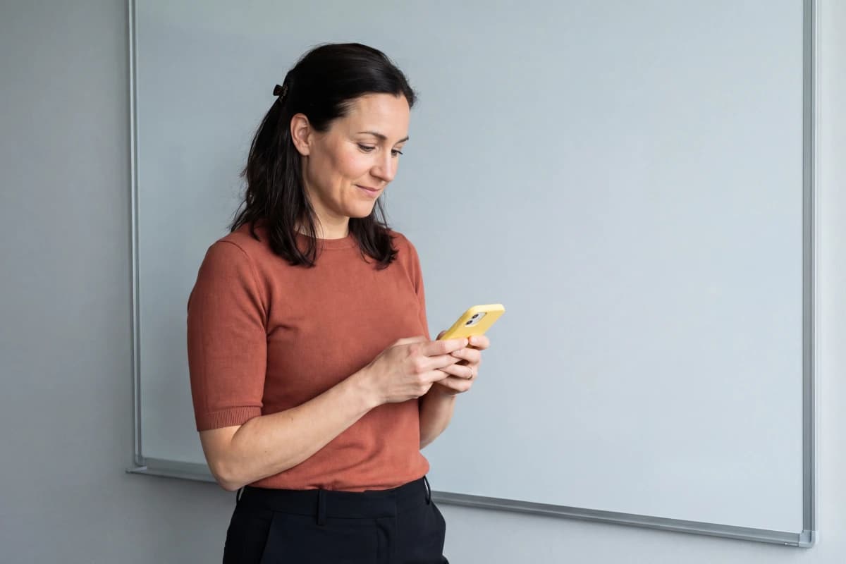 woman using yellow phone in an office with a whiteboard in the background